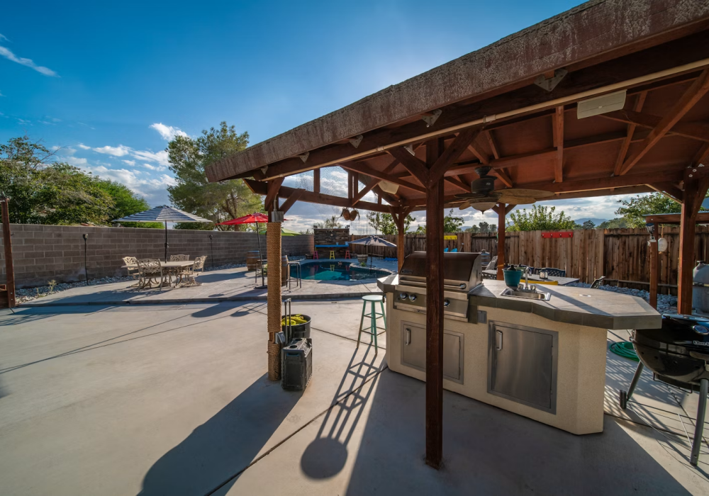 a covered patio with a grill and a table